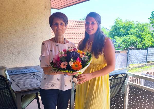 Frau Jessica Finsterle (Einsatzleitung Nachbarschaftshilfe) überreicht der Jubilarin Frau Jäger (links) einen Blumenstrauß